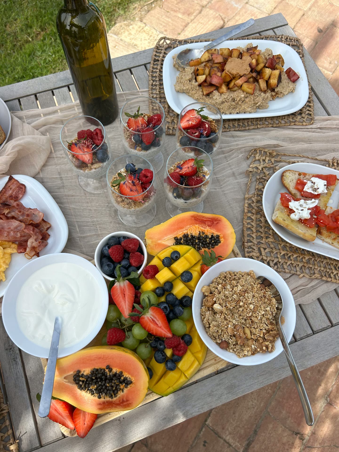 Table filled with fresh fruit, yoghurt, granola and warm breakfast dishes